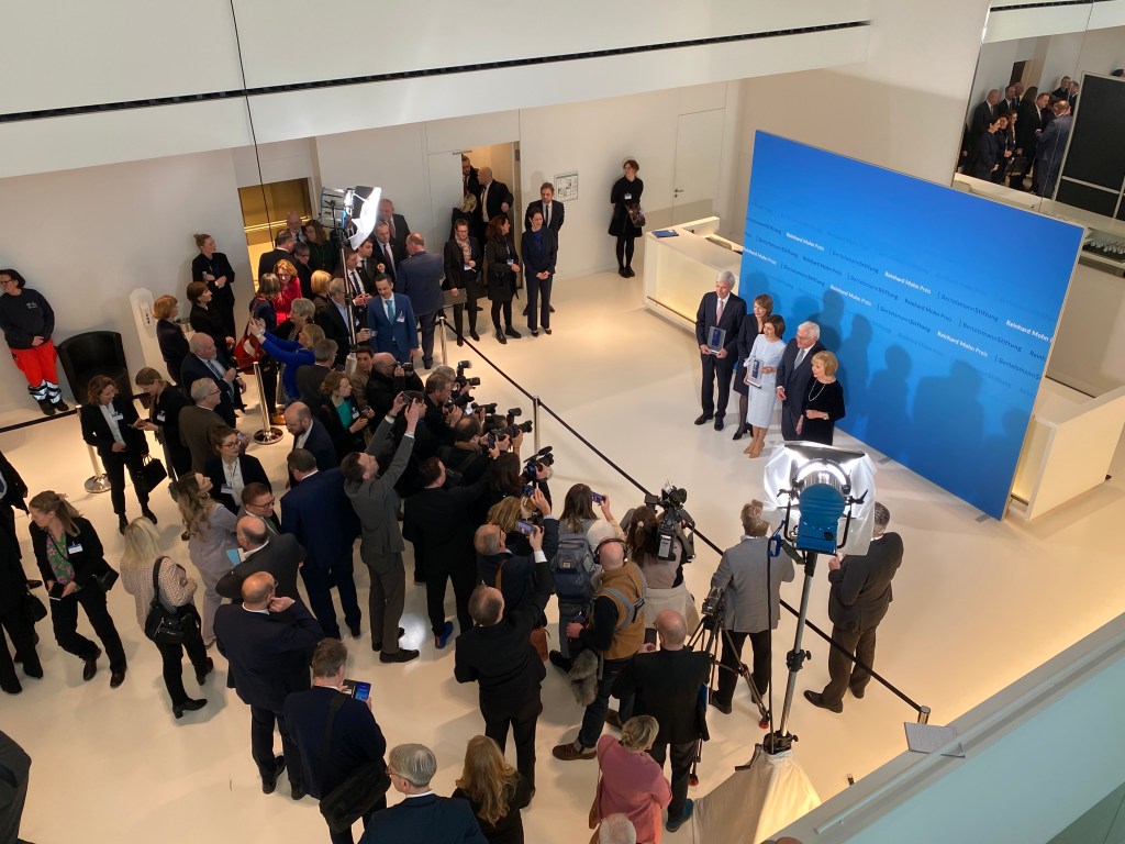 The winners of the Reinhard Mohn Preis 2025, Maia Sandu and Michael Otto, together with Federal President Frank-Walter Steinmeier, Liz Mohn in front of a sizeable crowd of press with cameras and microphones. Picture taken from above.